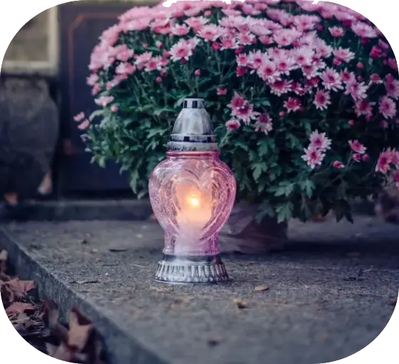 Candle in a pink candle holder with a large bunch of pink flowers in the background.